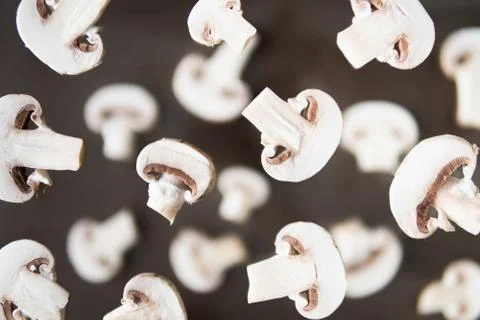 Pattern of sliced champignon mushrooms levitating above brown background Stock Photos