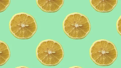 A pattern of sliced lemon fruit moving from left to right, over green background Stock Footage 243217540