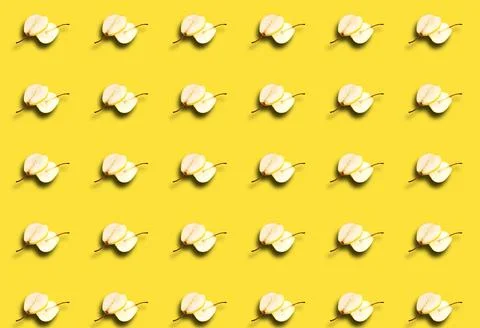 A pattern with slices of fresh pear cut in half on a yellow background. Fruit Stock Photos
