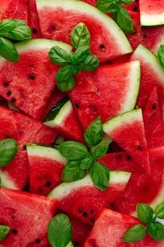 A pattern of slices of ripe watermelon and basil leaves Foto stock