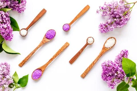 Pattern of spa sea salt in spoons with lilac flowers. Above view Stock Photos