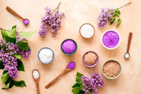 Pattern of spa sea salt in spoons with lilac flowers. Above view Stock Photos