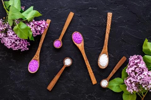 Pattern of spa sea salt in spoons with lilac flowers. Above view Stock Photos