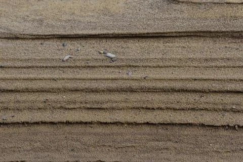 Pattern of straight, horizontal lines on dark sand Stock Photos