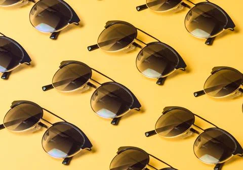 Pattern of sunglasses over a pastel yellow background with copy space minim.. Stock Photos