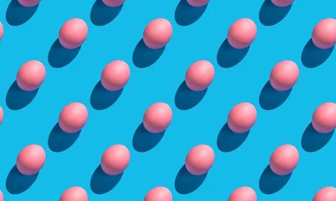 The pattern of their pink eggs with a hard shadow on a blue background. 스톡 사진