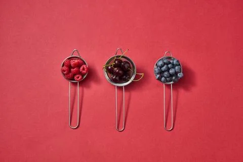 Pattern with three colanders with red juicy ripe cherry, raspberry, blueberry on Stock Photos