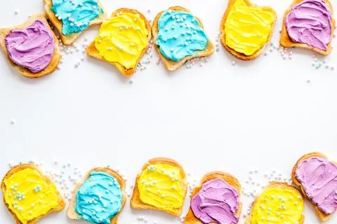 Pattern of toast bread with cheese spread, food dyes and sugary sprinkles. Stock Photos