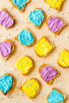 Pattern of toast bread with cheese spread, food dyes and sugary sprinkles. Stock Photos