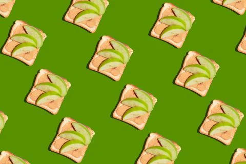 Pattern of toasted bread with apple and cinnamon on green background. Stock Photos
