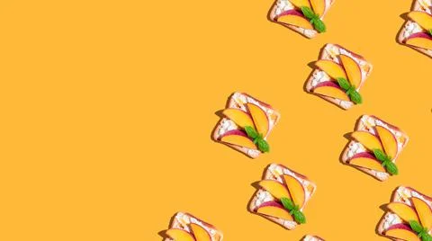 Pattern of toasted bread with peach and basil on yellow background. Stock Photos