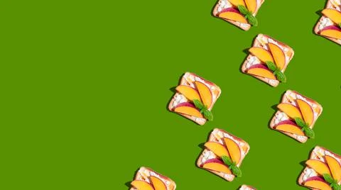 Pattern of toasted bread with peach and basil on green background. Stock Photos