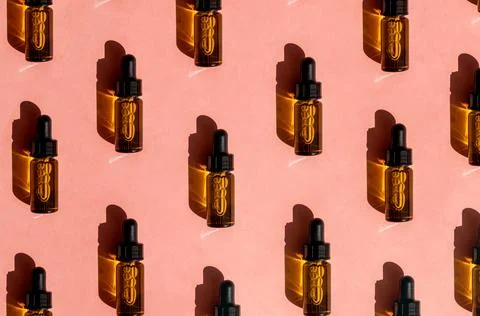 Pattern of Transparent amber glass dropper bottles with liquid inside on pink Stock Photos