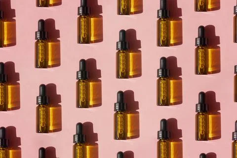 Pattern of transparent amber glass dropper bottles with liquid inside on beige Stock Photos