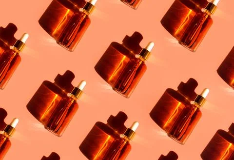 Pattern of Transparent amber glass dropper bottles with liquid inside on beige Stock Photos