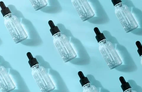 Pattern of transparent glass dropper bottle with air bubbles on blue background Stock Photos