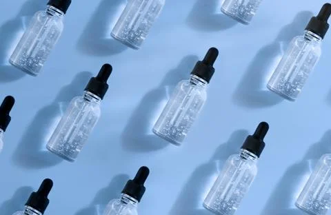 Pattern of transparent glass dropper bottle with air bubbles on blue background Stock Photos