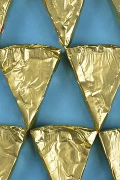 Pattern of triangular cheese portions in gold foil Stock Photos