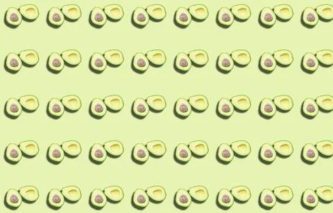 A pattern of two avocado halves with a shadow on a green background. Stock Photos