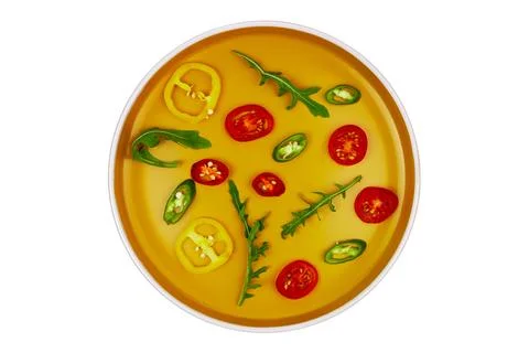 Pattern of vegetable slices on an orange plate isolated on white Stock Photos