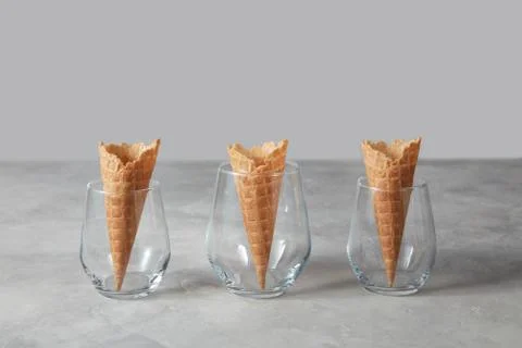 The pattern of wafer ice cream cones empty in the vases on a gray concrete table Foto stock