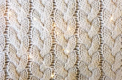 Pattern of warm winter autumn sweater close up, decorated with lights Stock Photos