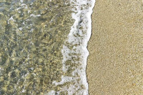 A pattern of waves crashes onto a rocky beach. View from above. Background, Foto stock