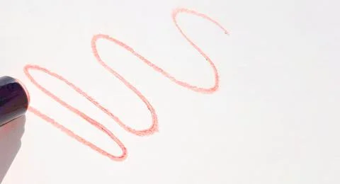 A pattern with wavy lines of red lipstick on a white background, the shadow o Stock Photos