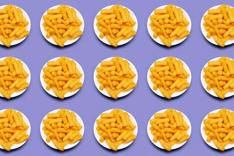 Pattern of white bowls with corn puffs on purple background. Stock Photos