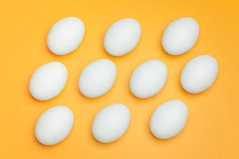 Pattern from white chicken eggs on yellow background top view. Creative food Stock Photos