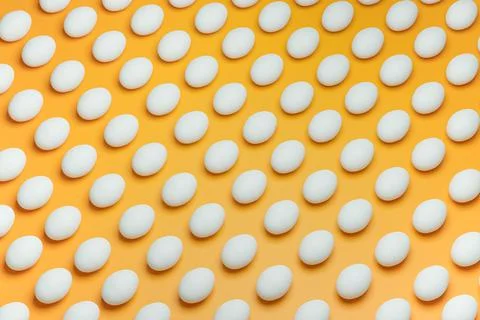 Pattern from white chicken eggs on yellow background top view. Creative food Stock Photos