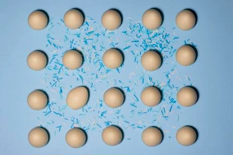 A pattern of white chocolate eggs with one tilted slideways on a blue background Stock Photos