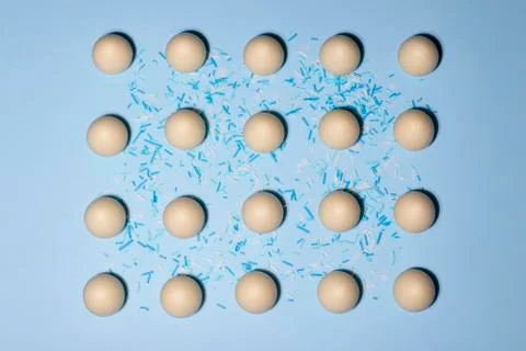 A pattern of white chocolate eggs was shot flat lay on a pale blue background Stock Photos