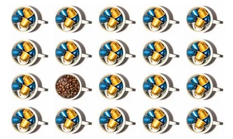 Pattern of white coffee cups full of coffee capsules, one cup with coffee beans Stock Photos