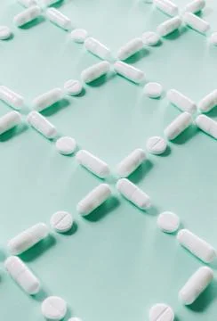 Pattern of white pills and tablets on a green background. Stock Photos