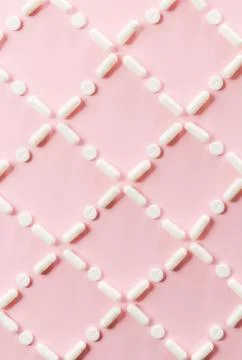 Pattern of white pills and tablets on a pink background. Stock Photos
