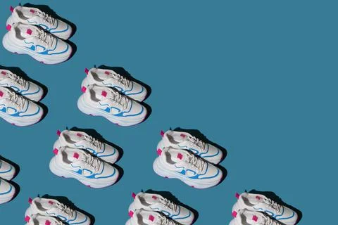 Pattern of white sneakers on a blue background. New sports shoes. Pair of casual Foto stock