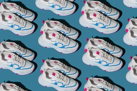 Pattern of white sneakers on a blue background. New sports shoes. Pair of casual Foto stock