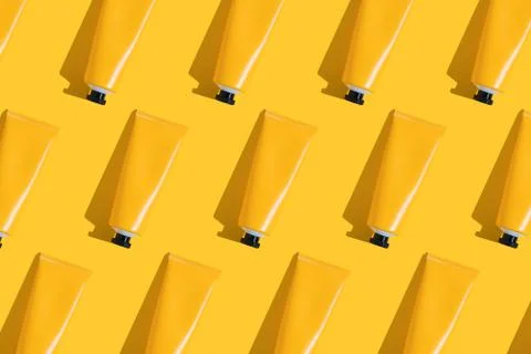 Pattern of yellow tubes of sunscreen on bright yellow background with hard Stock Photos