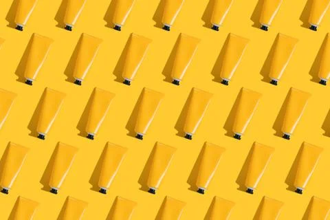 Pattern of yellow tubes of sunscreen on bright yellow background with hard Stock Photos