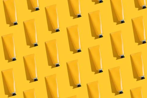 Pattern of yellow tubes of sunscreen on bright yellow background with hard Stock Photos