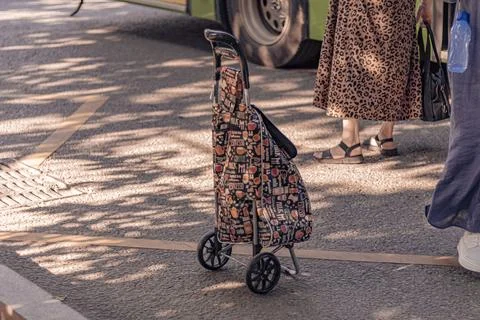 Patterned cart stands beside a bus stop Stock Photos