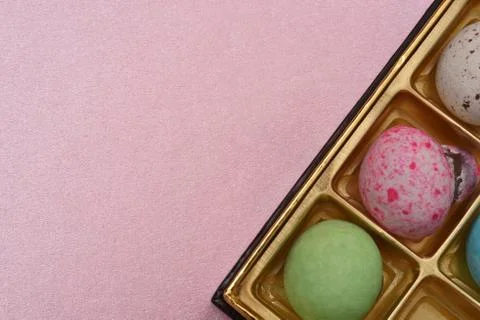 Patterned chocolate balls in box on pink paper background Stock-Fotos