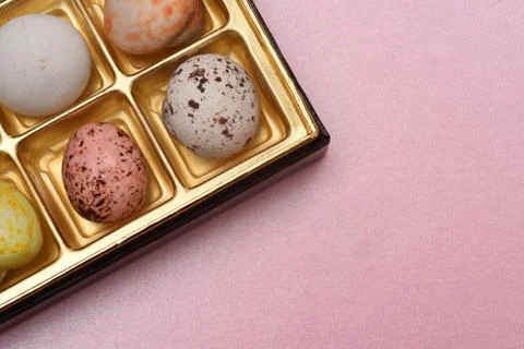 Patterned chocolate balls in box on pink paper background Stock-Fotos