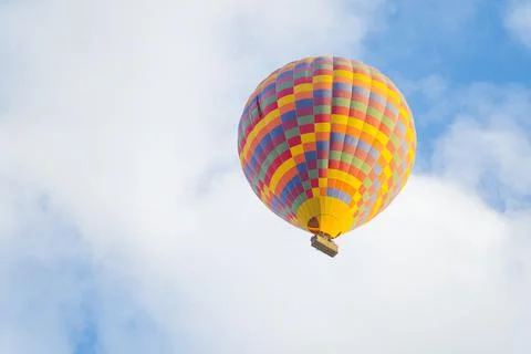 Patterned colourful hot-air balloon flying on the cloudy blue sky background Stock Photos