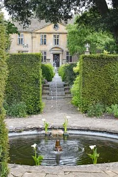 A patterned concrete block walkway between rounded topiary shrubs in an Engli Stock Photos