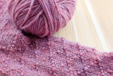 Patterned knitting with ball of pink yarn Foto stock