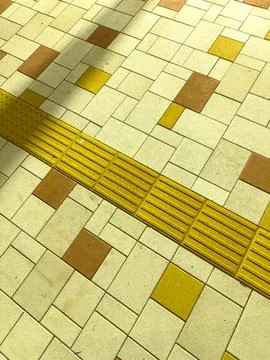 Patterned pavement with yellow guiding strips and colorful square tiles in .. Stock Photos