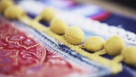 Patterned piece of cloth material with pom poms on denim patches at workshop Stock Footage 76539310