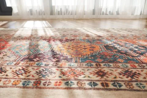 A patterned rug rests on the flooring beside a mirror Stock Photos